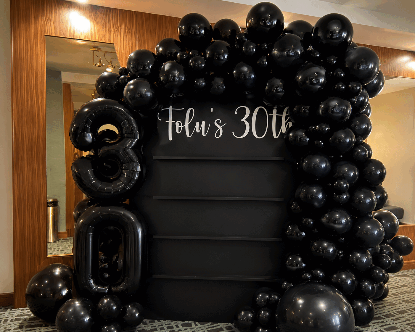 All-black balloon arch with a 30th birthday backdrop